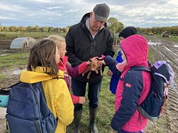 Das Foto zeigt Schülerinnen und Schüler der 5f mit einem jungen Schwein (November 2023).