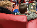 Das Foto zeigt zwei Schüler der 5f bei der Lesenacht in den roten Sesseln der Schülerbibliothek von hinten (November 2023).