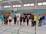 Das Foto zeigt die Schülerinnen und Schüler der 9ds in der TGG-Sporthalle um eine Tafel herum stehen.
