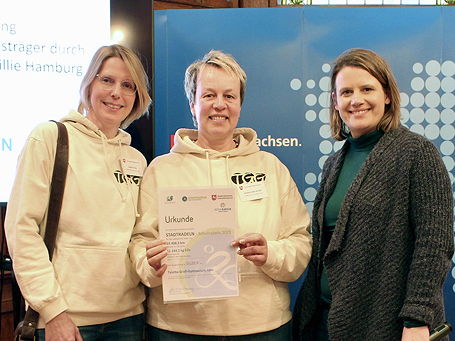 Das Foto zeigt die Klasse 6a mit ihrem Schneemann auf dem Pausenhof des TGG mit ihrem grünen Klassenmaskottchen (Dezember 2023).